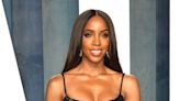 Kelly Rowland Teases ‘Legendary’ in Plunging Fringe Dress With Voluminous Plush Curls & Hidden Heels