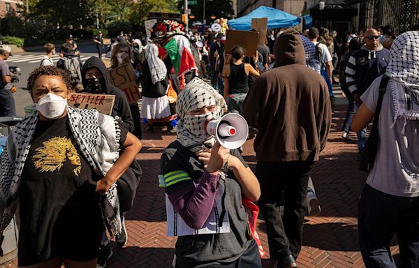 Masked anti-Israel protesters at Columbia University demonstrate as students check in for first day of classes