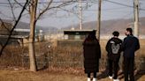 FILE PHOTO: A North Korean defector and his children stand in front of a barbed wire fence near the demilitarised zone separating the two Koreas, in Paju