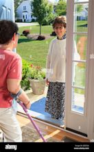 Woman with cerebral palsy greeting someone at the door of her home ...