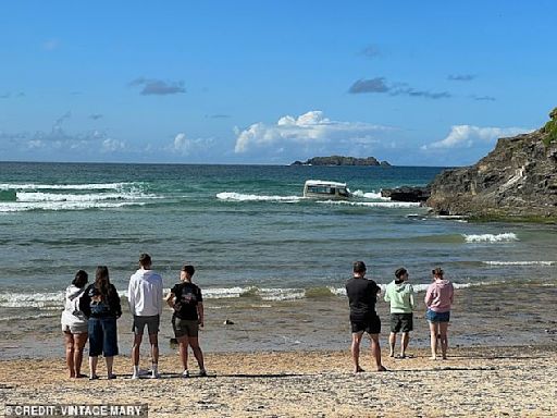 Whipped out to sea! Ice cream van is seen being buffeted by the waves