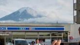 Tourists take pictures of Mount Fuji from opposite a convenience store in the town of Fujikawaguchiko, Yamanashi prefecture
