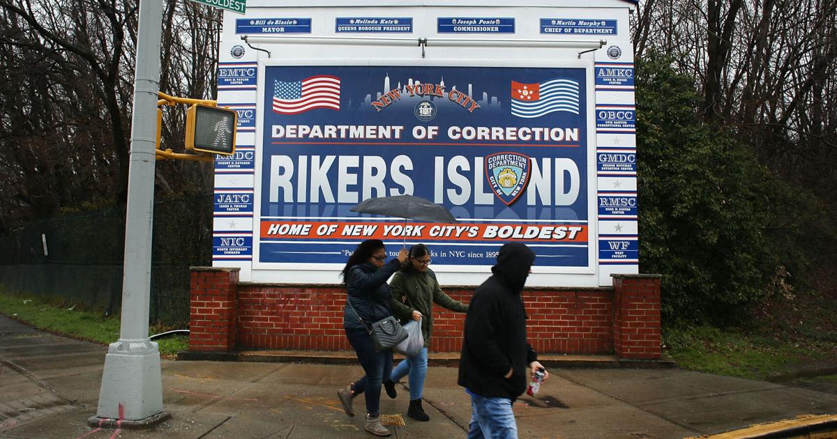 People walk by a sign at the entrance to Rikers Island on March 31, 2017 in New York City.