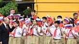 Putin (R) and Lam wave to children holding Vietnamese and Russian flags during a welcome ceremony in Hanoi on Thursday