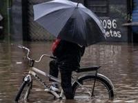 A local attempts to ride a bike in a flooded street at Santos Dumont neighbourhood in Sao Leopoldo, Rio Grande do Sul, Brazil, on May 12, 2024