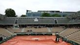 Spectators take shelter on Court Simonne Mathieu as rain swept across Roland Garros on Wednesday