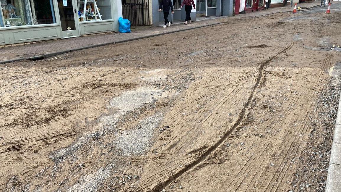 Flash flood rips up road and leaves it 'like beach'