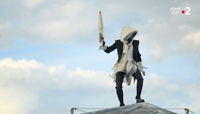 Cérémonie d’ouverture des JO : un homme masqué porte la flamme sur les toits de Paris