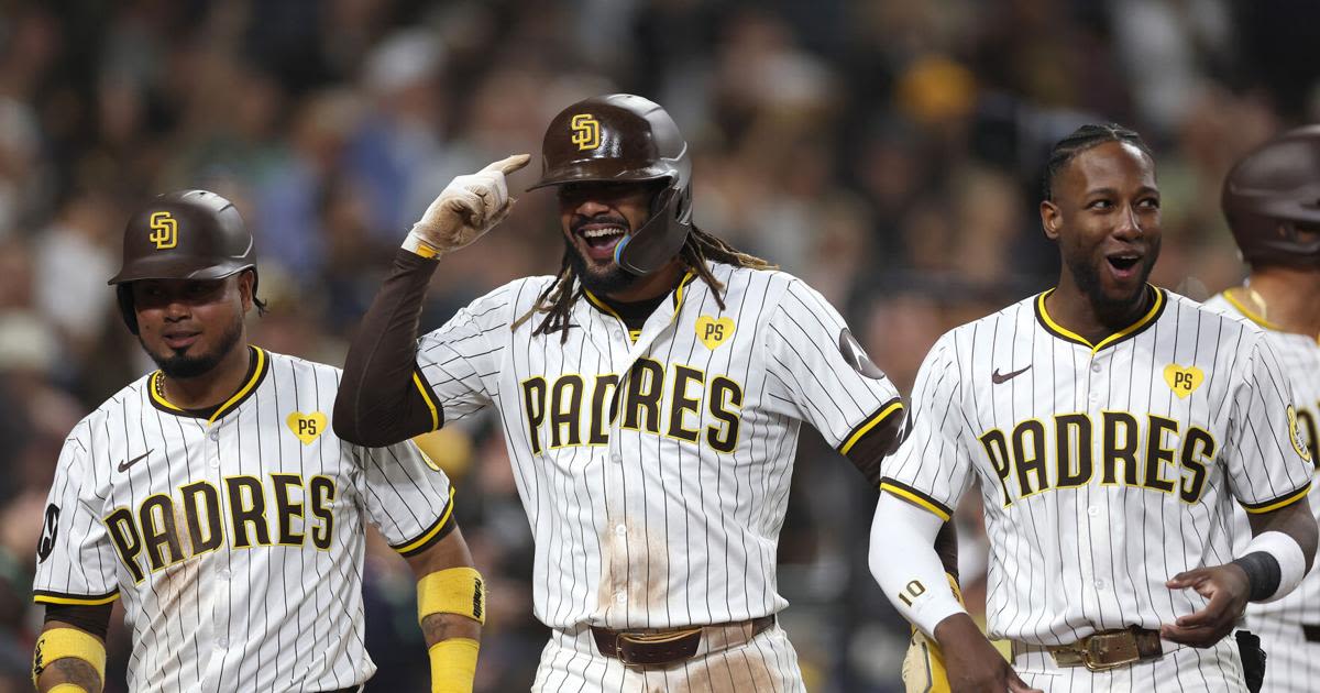 The San Diego Padres' Jurickson Profar, right, celebrates with Fernando Tatis Jr., middle, and Luis Arraez, left, after they scored on a throwing error during the fifth inning...