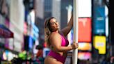 Body-positive surfer struts through Times Square in hot pink bikini and longboard to prove a point about 'women with curves'