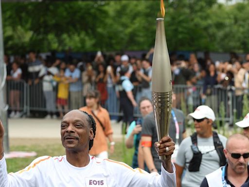 Snoop Dogg carries the Olympic torch before Opening Ceremony in Paris