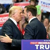 Republican nominee Donald Trump, wearing a new bandage on his ear after an attempted assassination, greets running mate J.D. Vance at a rally in Grand Rapids, Michigan