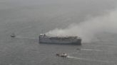 Tugs tow burning cargo ship to new location while salvage crews ponder next steps