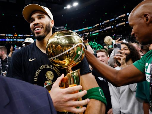 Jayson Tatum and the Boston Celtics carrying the NBA Championship trophy off the court