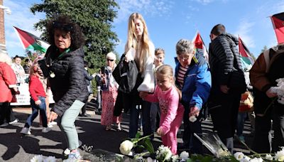 Schoolbags and white flowers left at gate of US Consulate in Belfast