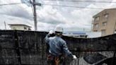 A worker installs a barrier to block the sight of Japan's Mount Fuji to deter badly behaved tourists, in the town of Fujikawaguchiko, Yamanashi prefecture