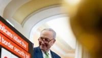 Senate Majority Leader Chuck Schumer stands next to a poster that reads "Republicans killed the toughest border security bill 98 days ago. Democrats are ready to act"