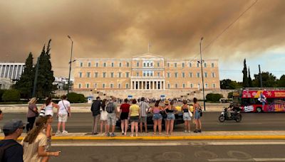 A wildfire near Greece's capital darkens the skies over Athens and advances fast