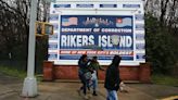 People walk by a sign at the entrance to Rikers Island on March 31, 2017 in New York City.