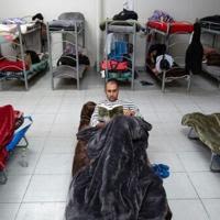 Sammir Mohmer, from Afghanistan, reads in a dorm at the Assabil migrant shelter