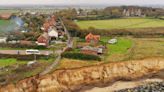 Photos show how a Medieval English village with a 14th-century church and historic lighthouse is crumbling into the sea