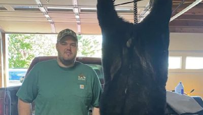 Maine hunter poses proudly beside biggest bear killed so far this year