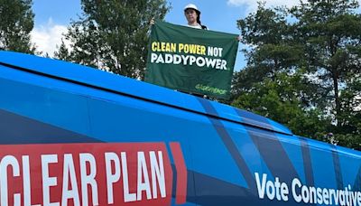 Greenpeace protester climbs on top of Conservative election campaign bus