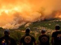 Firefighters watch as flames and smoke move through a valley in the Forest Ranch area of Butte County as the Park Fire continues to burn near Chico, California, on July 26, 2024