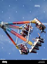 People enjoying high fairground ride against blue sky Stock Photo - Alamy