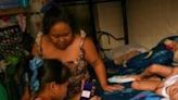 Cindella Manabat (C) helps her daughter Ella Araza (L) with homework, at their house in Manila