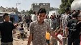 A youth walks with a bucket of water from a tanker cistern in Deir el-Balah in the central Gaza Strip on April 30, 2024