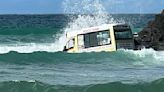 Whipped out to sea! Ice cream van is seen being buffeted by the waves