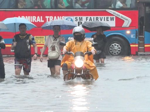 People swim, drive and wade through deep floodwater in Manila