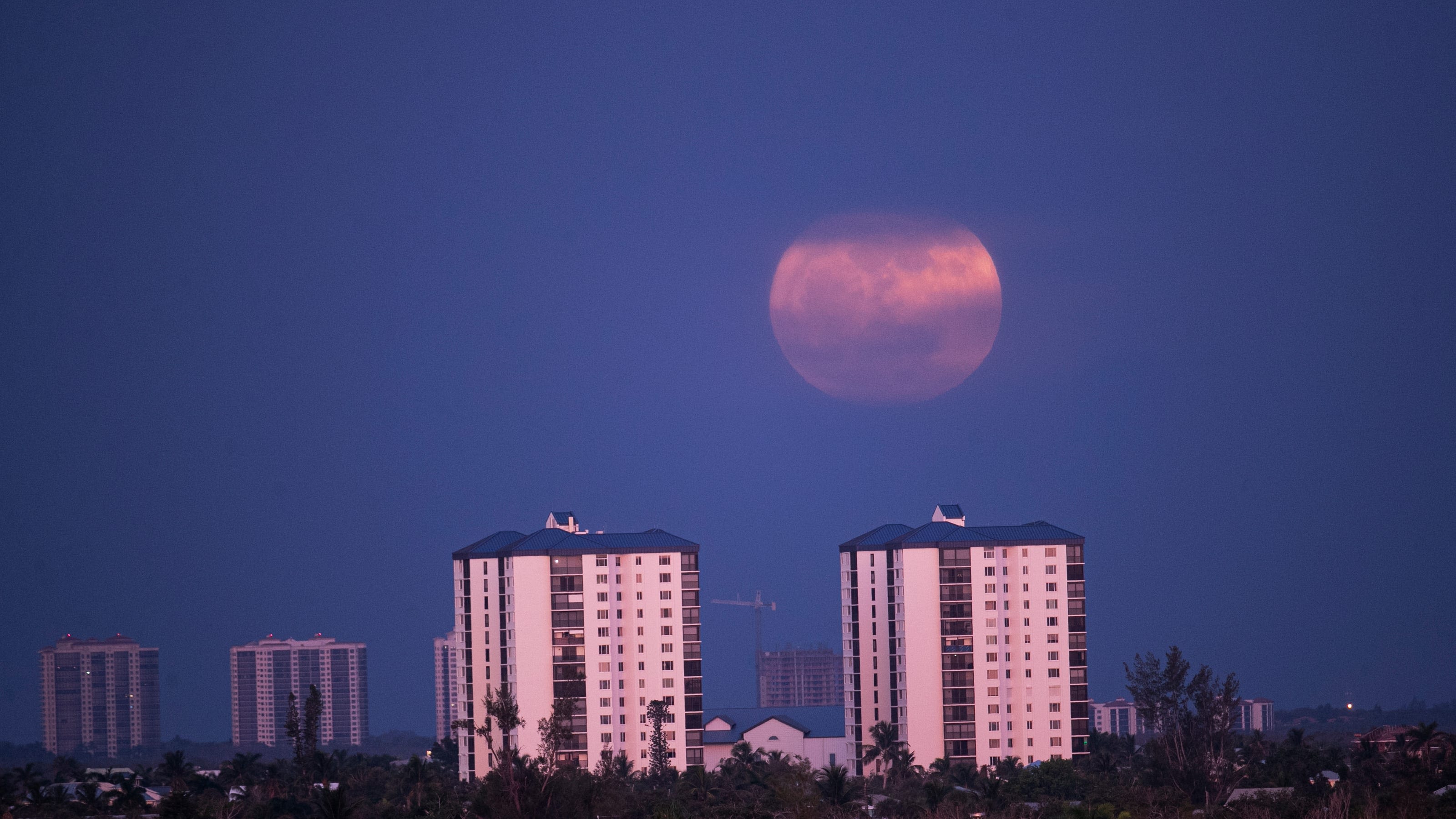 Full moon and summer solstice fall on same day. Strawberry moon peeks out briefly above horizon