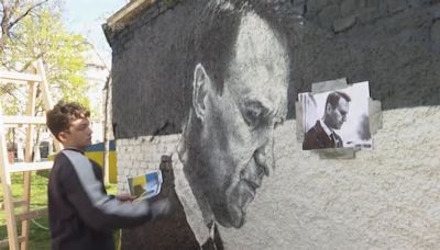 Artists spray-paint portraits of Alexei Navalny behind a Soviet monument in Vienna