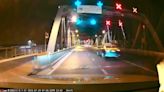 Strolling monitor lizard holds up traffic on busy Thailand bridge