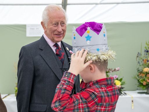 Schoolboy tries on prize-winning cardboard crown in front of the King