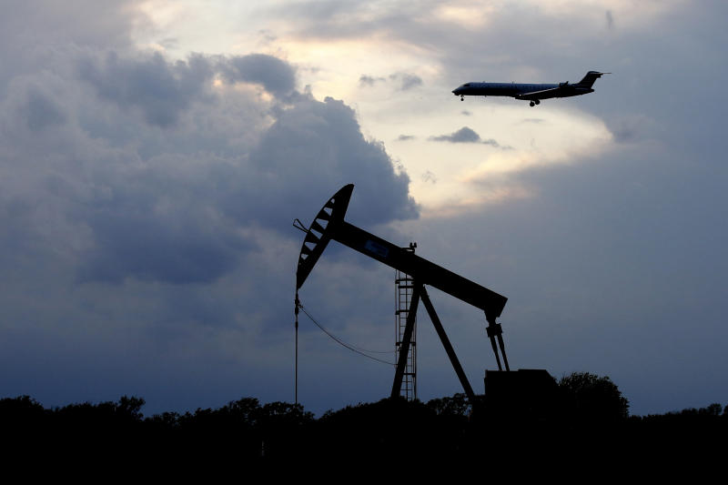 FILE - In this April 21, 2020, file photo, a plane comes in for a landing behind a pumpjack in Oklahoma City. Oil prices continue to drop, because very few people are flying or driving, and factories have shut amid widespread stay-at-home orders due to the coronavirus concerns. The Oklahoma Corporation Commission approved an emergency order on Wednesday, April 22, 2020, that allows oil producers to stop or cut back production without losing their leases for non-production. (AP Photo/Sue Ogrocki File)