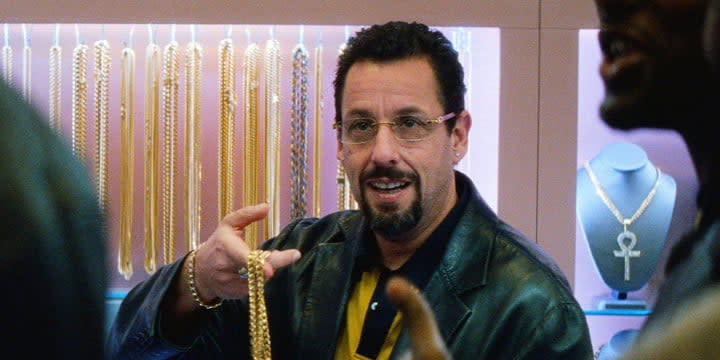 adan sandler usando lentes para ver y sosteniendo algo en sus manos