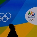 A journalist walks in front of a screen with olympics logos during the medal launching ceremony in Rio de Janeiro, Brazil, June 14, 2016. REUTERS/Sergio Moraes