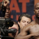 Floyd Mayweather Jr. poses on the scale as Manny Pacquiao's trainer Freddie Roach, second from lower left, closely watches, during his weigh-in on Friday, May 1, 2015 in Las Vegas. The world weltherweight title fight between Mayweather Jr. and Manny Pacquiao is scheduled for May 2. (AP Photo/Chris Carlson)