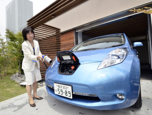 A Nissan employee demonstrates charging one of the country's Leaf electric vehicles using a smart home electricity supply cable in Yokohama, suburban Tokyo