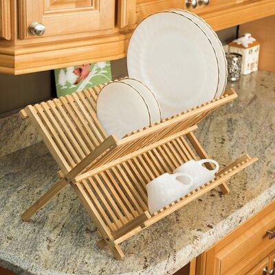 Dish Rack Holds Many Dishes And Cups Against Wooden Countertop