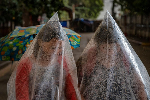 Residents in Talisay use plastic bags to shield themselves from ash and rainwater on Jan. 12. | Ezra Acayan—Getty Images