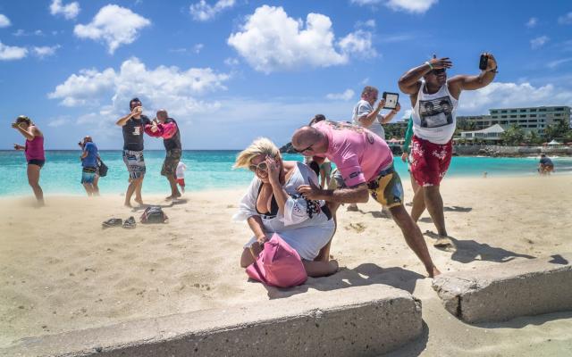 Tourists experience the blast of an aircraft on a nearby beach - Credit: GETTY