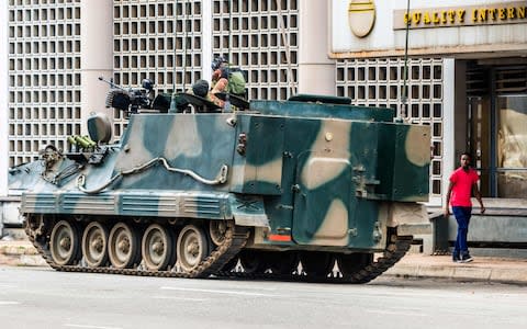 A man walks past a military tank parked on the side of a street in the Zimbabwean capital Harare on November 16, 2017 - Credit: STR/AFP 