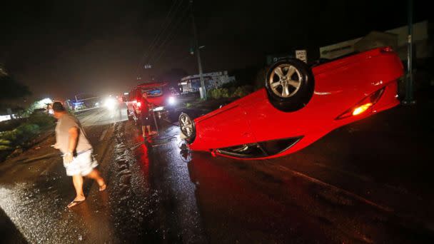 PHOTO: People tend to a car that flipped over on Cape Coral Parkway during Hurricane Irma, in Cape Coral, Fla., Sept. 10, 2017. (Gerald Herbert/AP)