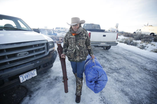 In this Jan. 6, 2016 photo, Arizona rancher LaVoy Finicum carries his rifle after standing guard all night at the Malheur National Wildlife Refuge near Burns, Ore. (AP photo/Rick Bowmer)