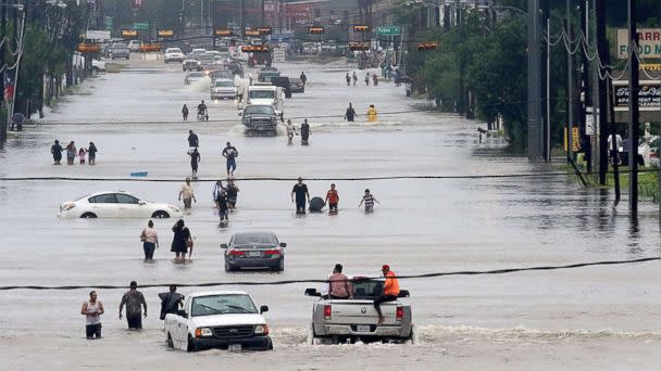 PHOTO: People walk through the flooded waters of Telephone Rd. in Houston, Aug. 27, 2017, as the city battles with tropical storm Harvey and resulting floods. (Thomas B. Shea/AFP/Getty Images)