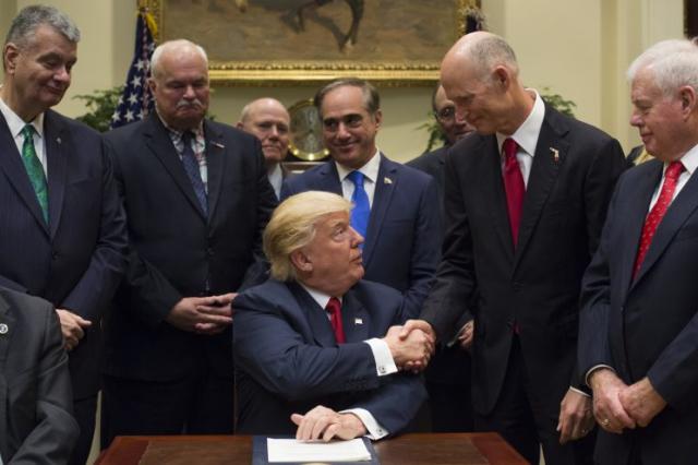 U.S. President Donald Trump, center, shakes hands with Rick Scott, governor of Florida, after signing bill S. 544, the Veterans Choice Program Extension and Improvement Act, in the Roosevelt Room of the White House in Washington, D.C., U.S., on Wednesday, April 19, 2017 The bill extends a program allowing eligible veterans to seek medical care from private health-care providers. (Photo: Molly Riley/Pool via Bloomberg)